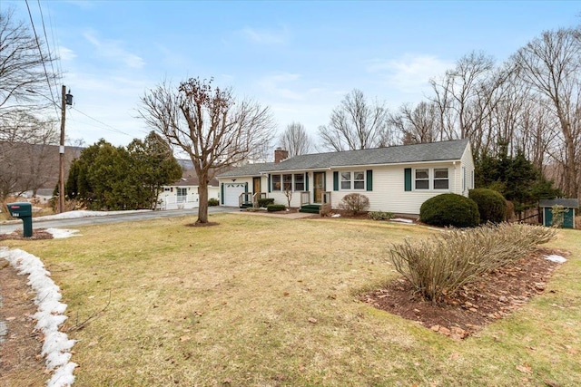 ranch-style home featuring a garage, a front yard, a chimney, and driveway