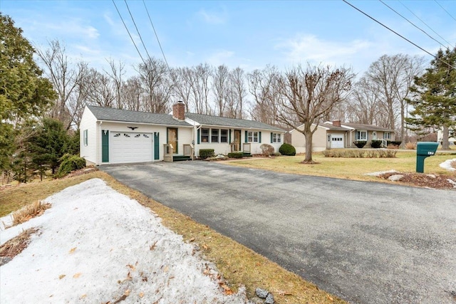 single story home with a garage, a front yard, a chimney, and driveway