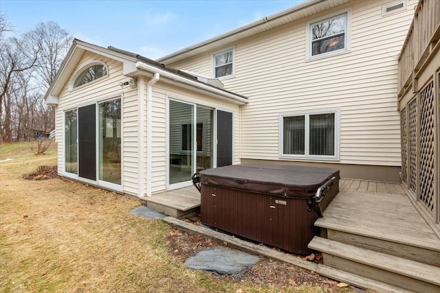 rear view of property featuring a hot tub and a deck