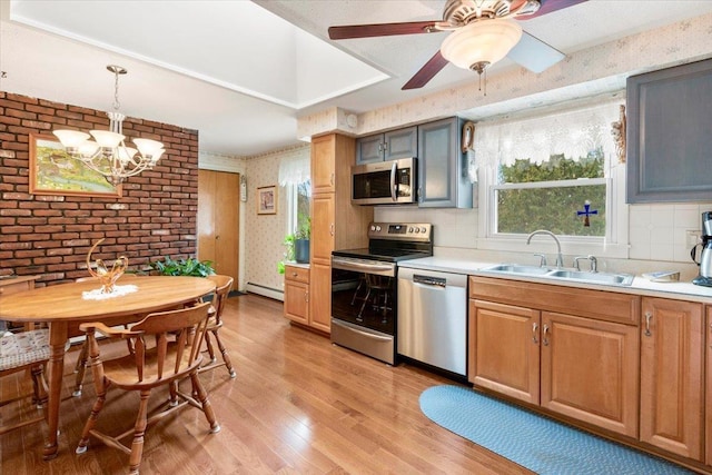 kitchen with light wood-style flooring, a sink, stainless steel appliances, wallpapered walls, and a baseboard radiator