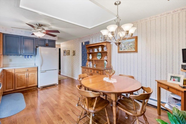 dining room featuring wallpapered walls, ceiling fan with notable chandelier, light wood-style floors, and baseboards