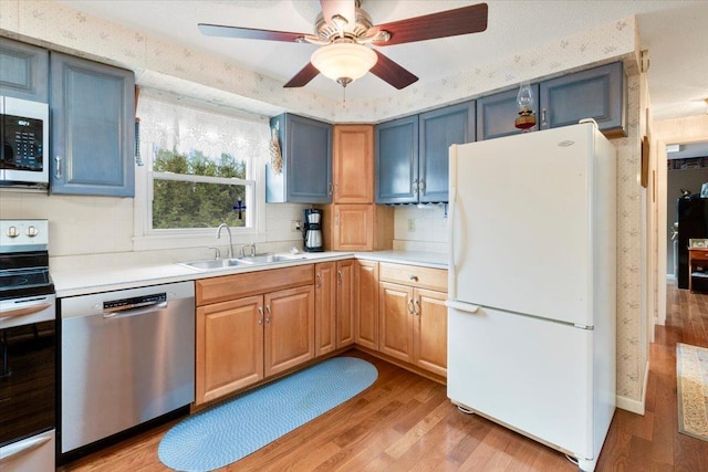 kitchen featuring light wood-type flooring, a sink, stainless steel appliances, light countertops, and decorative backsplash