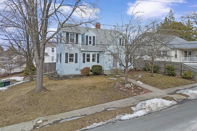 view of front of house with a gambrel roof, a front lawn, fence, roof with shingles, and a chimney