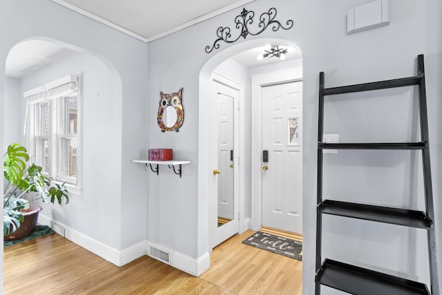 foyer featuring visible vents, baseboards, wood finished floors, and crown molding