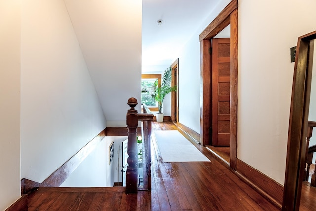 hall with an upstairs landing and wood-type flooring