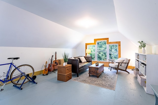 living area with baseboards, concrete flooring, and vaulted ceiling