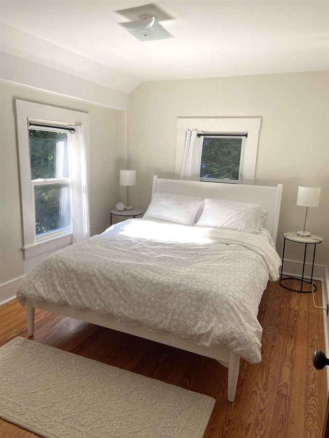 bedroom featuring vaulted ceiling, wood finished floors, and baseboards