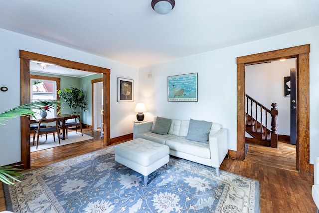 living room featuring baseboards, wood finished floors, and stairs