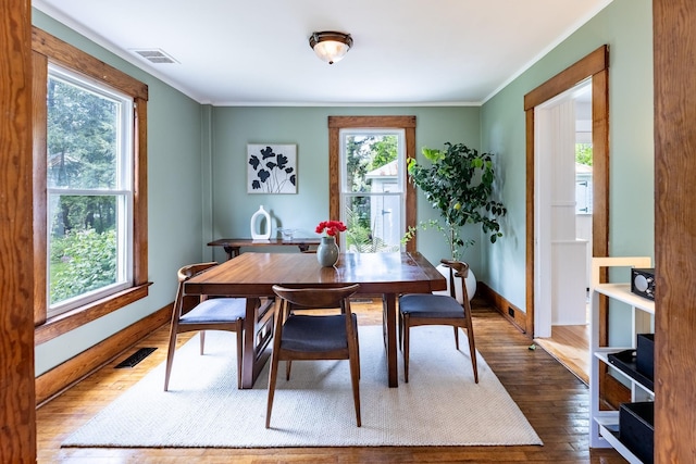 dining space featuring visible vents, baseboards, dark wood-style floors, and ornamental molding