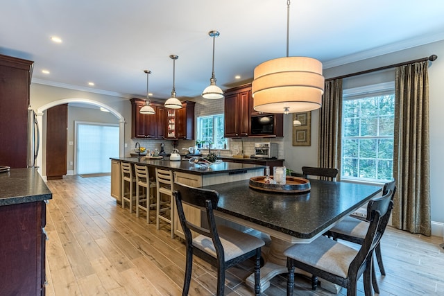 kitchen with dark countertops, tasteful backsplash, arched walkways, and black microwave