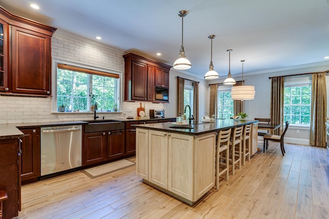 kitchen featuring a breakfast bar, a sink, tasteful backsplash, stainless steel dishwasher, and light wood finished floors