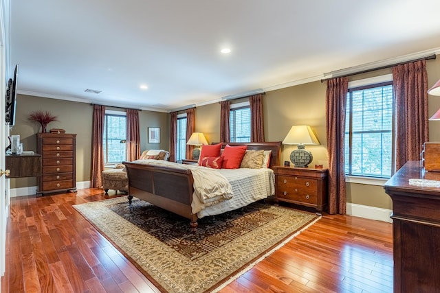 bedroom featuring visible vents, baseboards, crown molding, and hardwood / wood-style flooring