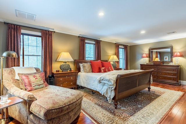 bedroom with visible vents, wood finished floors, and ornamental molding