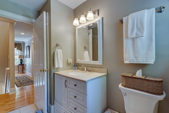 bathroom with vanity, toilet, wood finished floors, and baseboards