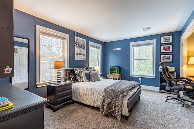 carpeted bedroom featuring multiple windows, baseboards, and visible vents