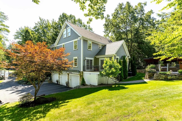 view of side of property with a lawn, aphalt driveway, stairway, roof with shingles, and a garage