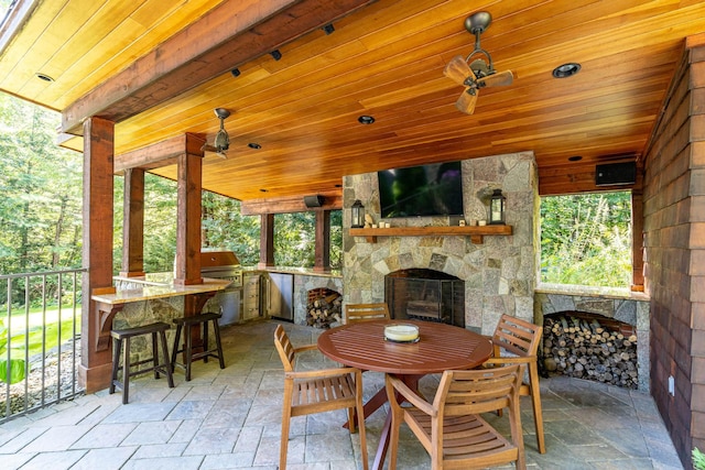 view of patio with an outdoor kitchen, outdoor dining space, grilling area, and an outdoor stone fireplace