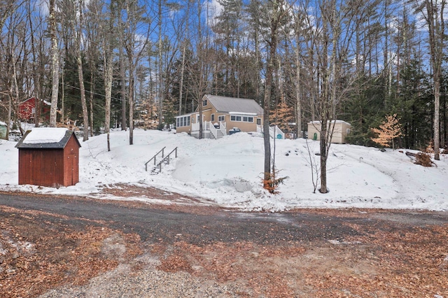 yard covered in snow featuring a storage unit and an outbuilding