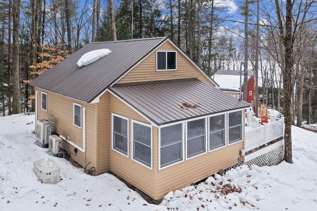 snow covered rear of property with metal roof and a sunroom