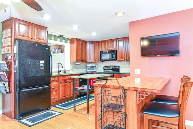 kitchen featuring tasteful backsplash, a breakfast bar area, black appliances, and a sink