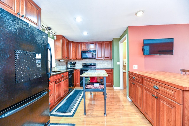 kitchen featuring recessed lighting, black appliances, light wood-type flooring, backsplash, and butcher block counters