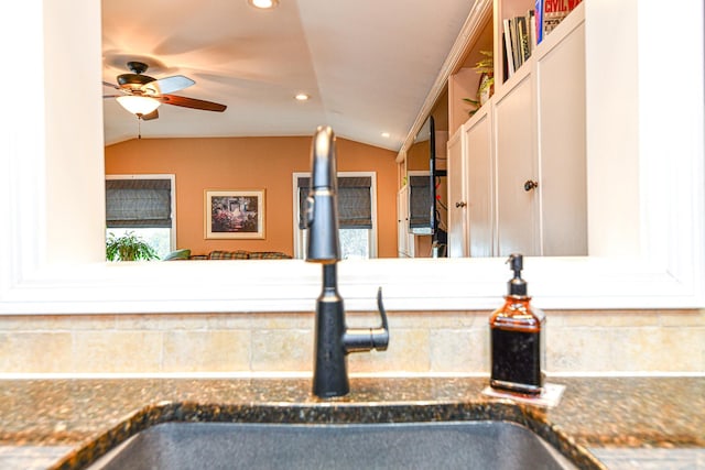 kitchen with a ceiling fan, a sink, dark stone countertops, recessed lighting, and vaulted ceiling