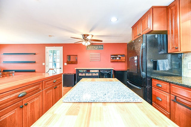 kitchen with backsplash, butcher block counters, black appliances, and brown cabinets