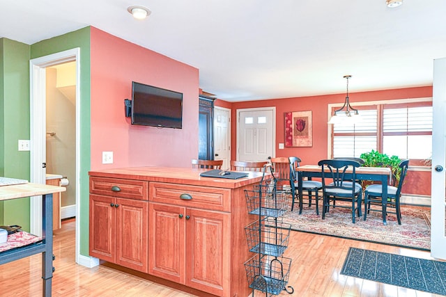 kitchen featuring decorative light fixtures, baseboard heating, light wood-style flooring, and light countertops