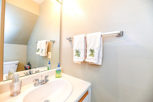 bathroom featuring toilet, vanity, and lofted ceiling