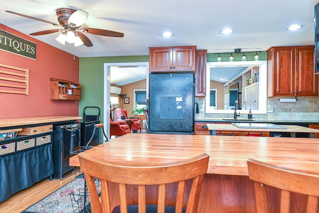 kitchen featuring lofted ceiling, light wood-style flooring, freestanding refrigerator, decorative backsplash, and wood counters