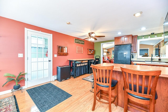 kitchen featuring wooden counters, a breakfast bar, black refrigerator, and light wood-style floors