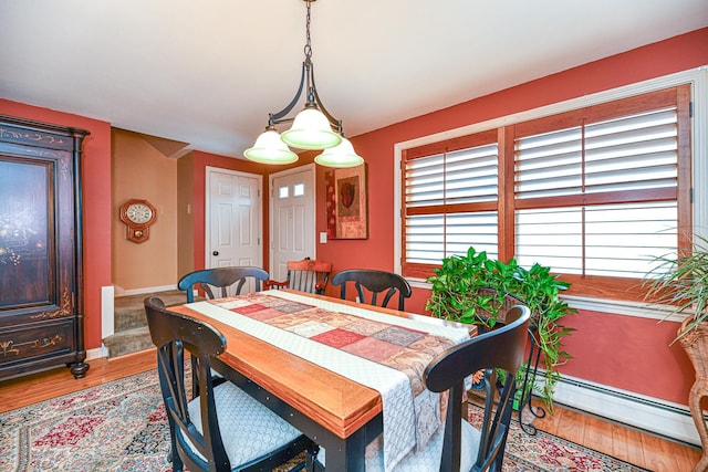 dining space featuring wood finished floors, stairs, baseboards, and a baseboard radiator