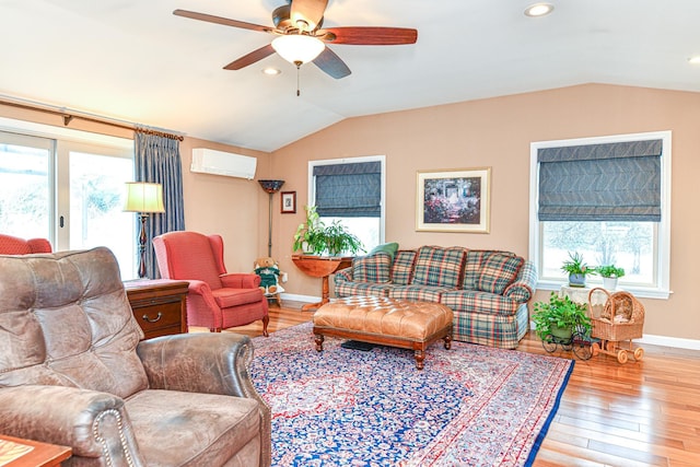 living area featuring vaulted ceiling, plenty of natural light, light wood finished floors, and a wall mounted AC