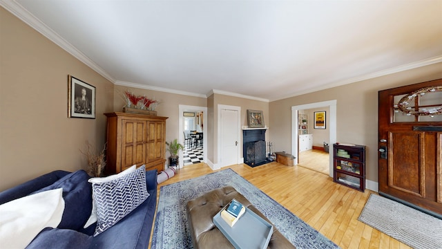 living room featuring a fireplace, light wood-type flooring, baseboards, and crown molding