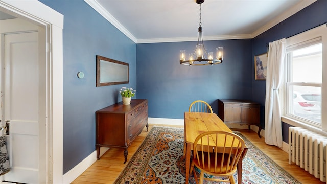 dining area with baseboards, radiator heating unit, ornamental molding, an inviting chandelier, and light wood-style floors