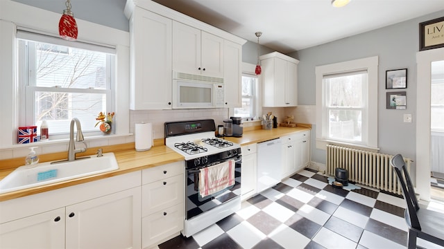 kitchen featuring a sink, white cabinetry, white appliances, light countertops, and light floors