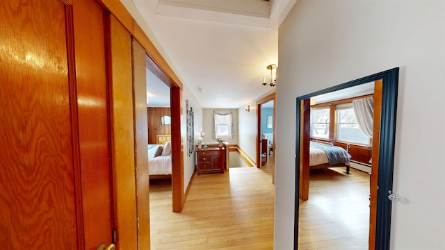 hall featuring a baseboard radiator, plenty of natural light, and light wood-style floors