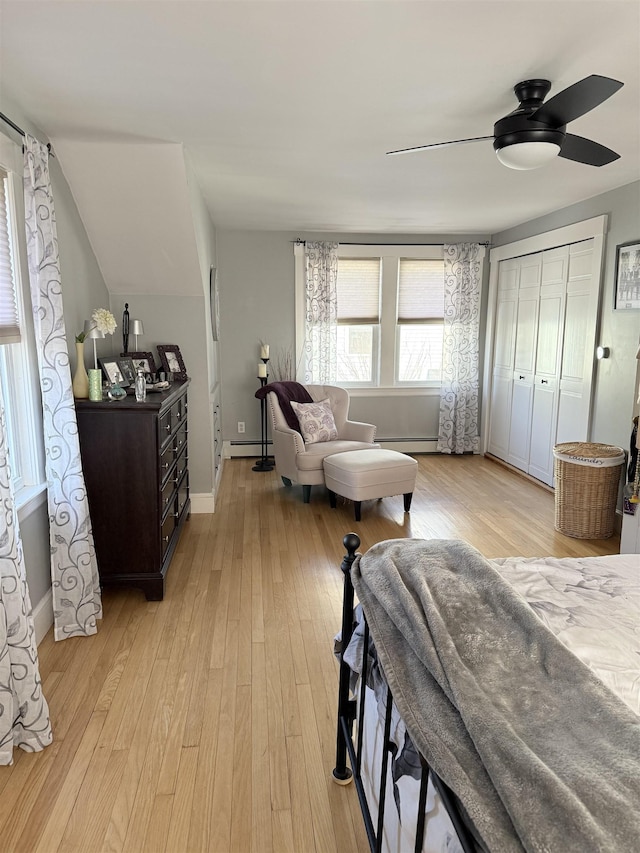 bedroom with baseboard heating, a ceiling fan, light wood-type flooring, and baseboards