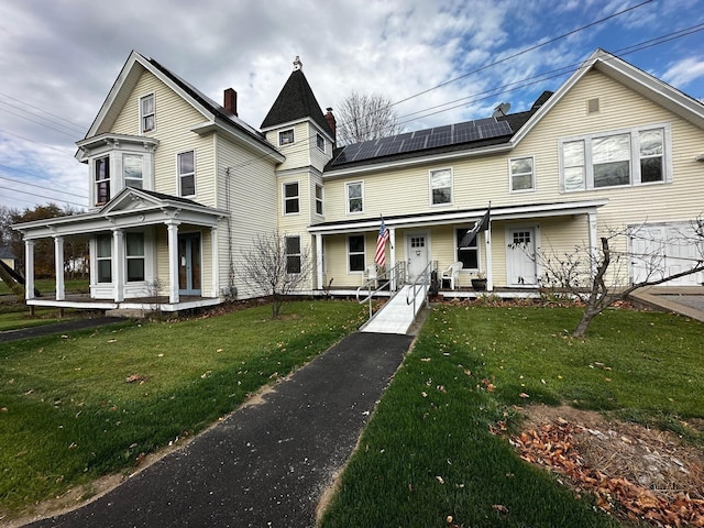 victorian house with a front lawn, covered porch, and roof mounted solar panels