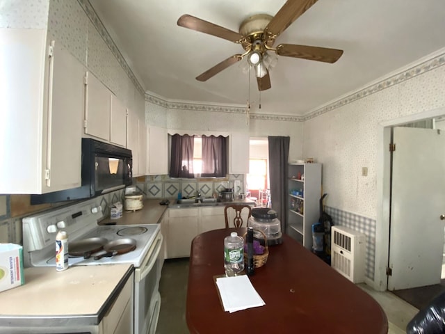 kitchen with a sink, white cabinetry, white electric stove, black microwave, and wallpapered walls