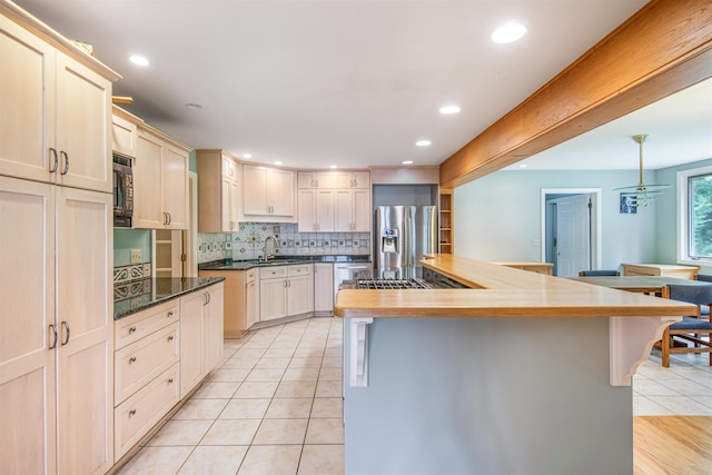 kitchen with tasteful backsplash, light tile patterned floors, recessed lighting, stainless steel fridge, and a sink