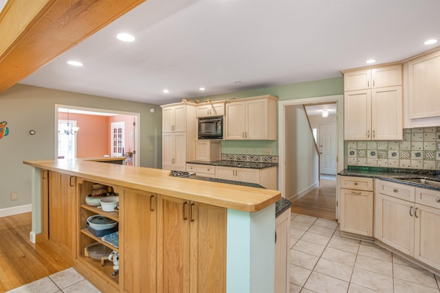 kitchen with light tile patterned flooring, recessed lighting, black microwave, tasteful backsplash, and a center island