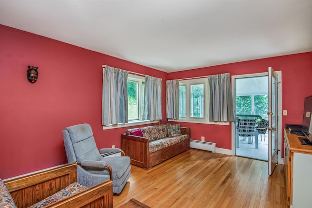 living area featuring light wood-style floors, a wealth of natural light, and a baseboard radiator