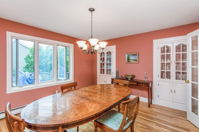 dining room featuring baseboards, a baseboard heating unit, light wood-type flooring, and an inviting chandelier