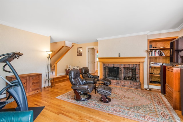 living area featuring crown molding, a brick fireplace, wood finished floors, and baseboards