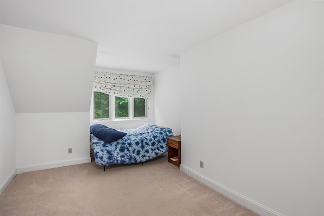 bedroom featuring light carpet, lofted ceiling, and baseboards