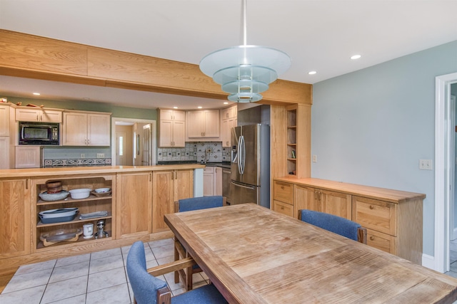 kitchen with wooden counters, light tile patterned flooring, stainless steel refrigerator with ice dispenser, black microwave, and tasteful backsplash