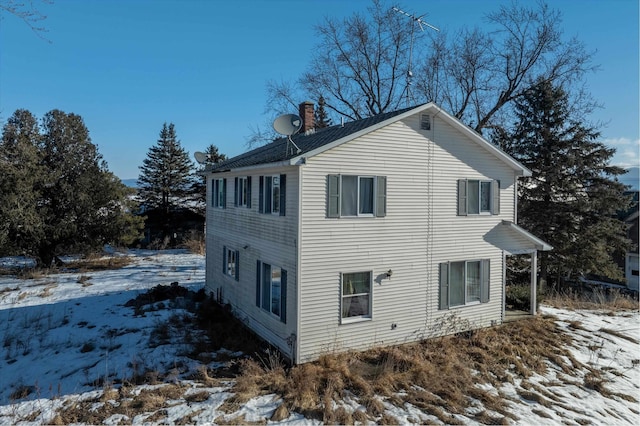 view of snow covered exterior with a chimney