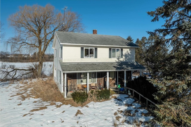 view of front of property with covered porch, roof with shingles, and a chimney