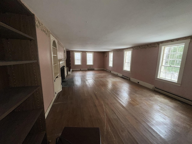 unfurnished living room featuring dark wood-style floors, baseboard heating, a fireplace, and baseboards